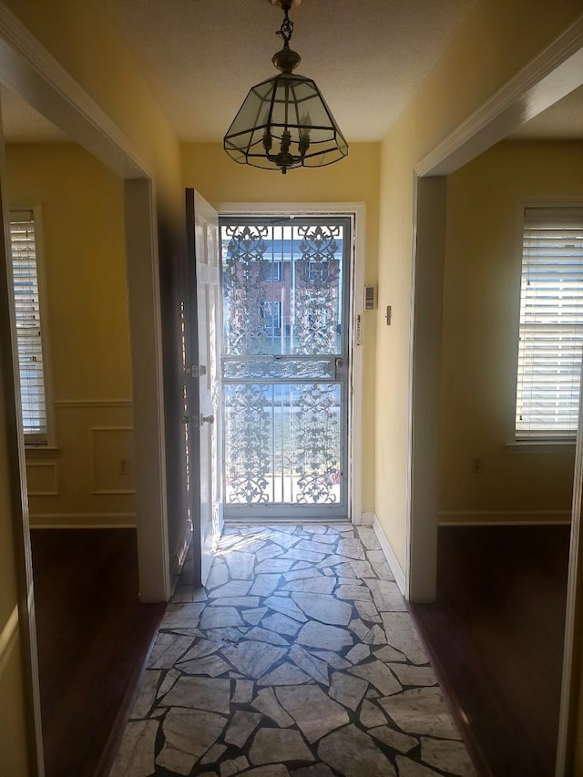 doorway with a chandelier and dark wood-type flooring