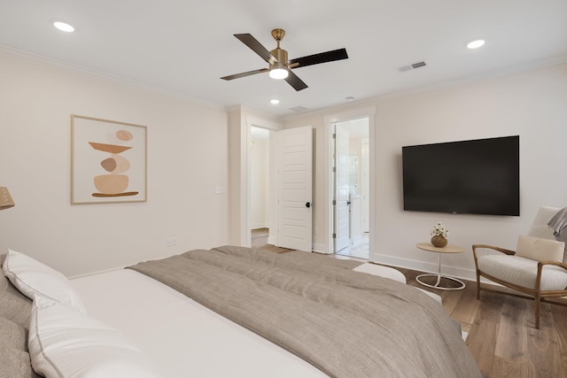 bedroom featuring wood-type flooring, ensuite bath, ceiling fan, and crown molding