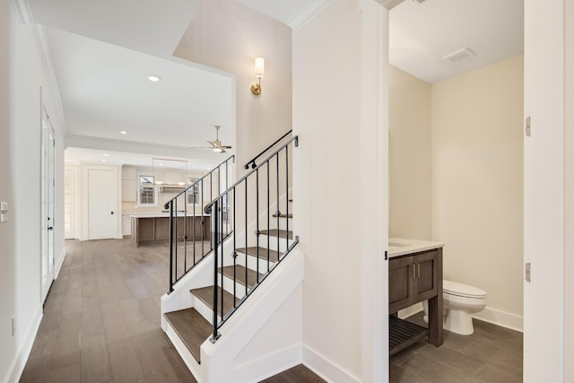 stairway featuring ceiling fan, hardwood / wood-style floors, and ornamental molding