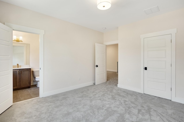 unfurnished bedroom with ensuite bath and light carpet