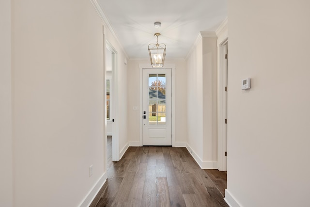 doorway with dark hardwood / wood-style flooring, crown molding, and an inviting chandelier