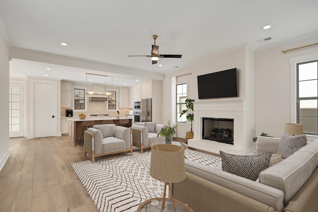 living room featuring light hardwood / wood-style flooring, a healthy amount of sunlight, and ornamental molding