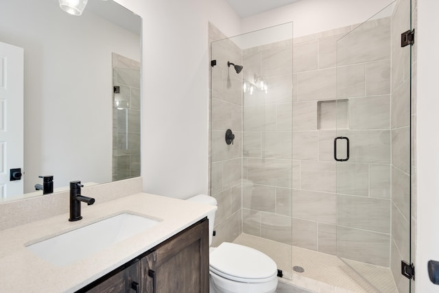 bathroom with an enclosed shower, vanity, and toilet