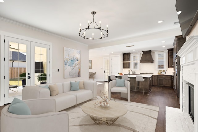 living room featuring an inviting chandelier, french doors, ornamental molding, a fireplace, and dark hardwood / wood-style flooring