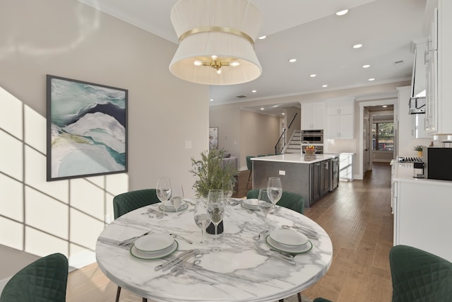 dining area with dark hardwood / wood-style flooring, ornamental molding, and a notable chandelier