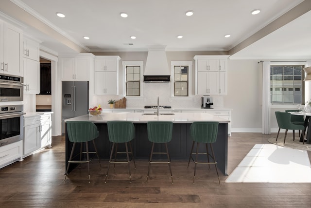 kitchen featuring white cabinetry, dark wood-type flooring, a large island with sink, a breakfast bar, and custom exhaust hood