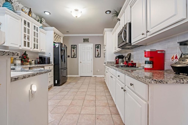 kitchen with light tile patterned floors, white cabinetry, stainless steel appliances, ornamental molding, and light stone countertops