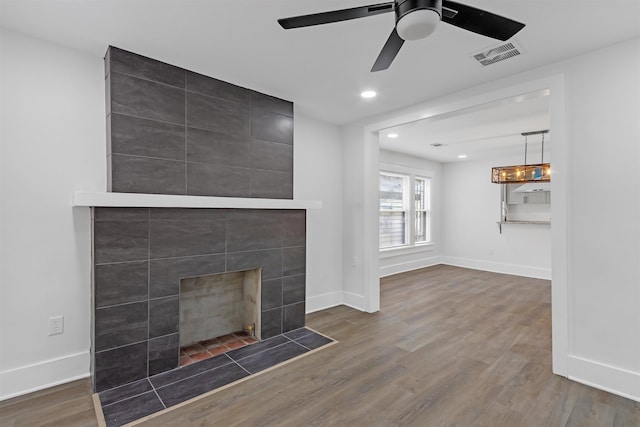 unfurnished living room featuring a tile fireplace, ceiling fan, and hardwood / wood-style flooring