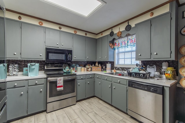 kitchen with appliances with stainless steel finishes, backsplash, gray cabinets, and sink