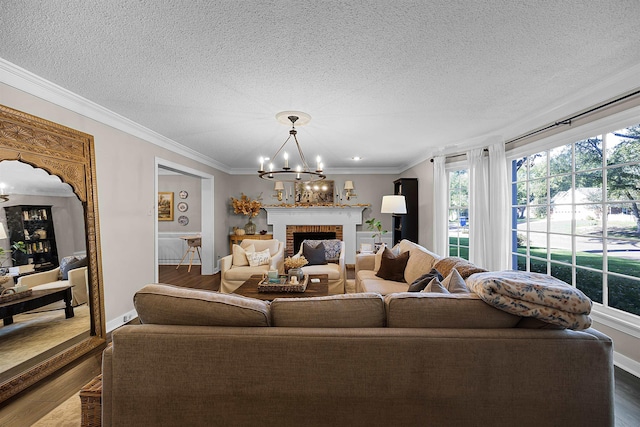 living room with a textured ceiling, crown molding, wood-type flooring, an inviting chandelier, and a fireplace