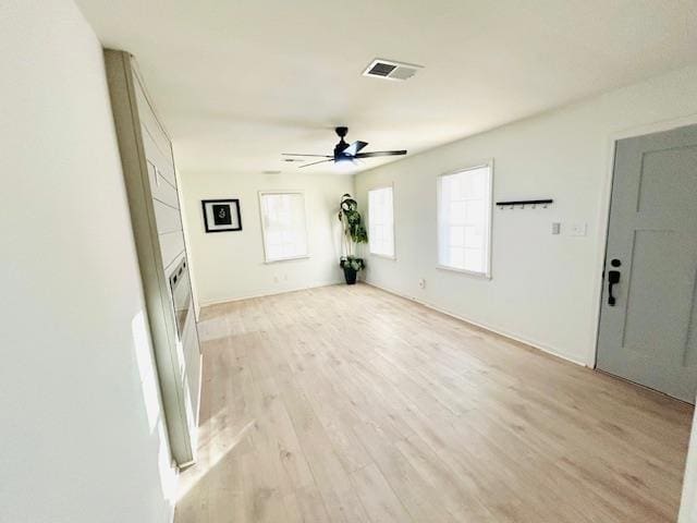 unfurnished living room featuring light wood-type flooring, plenty of natural light, and ceiling fan