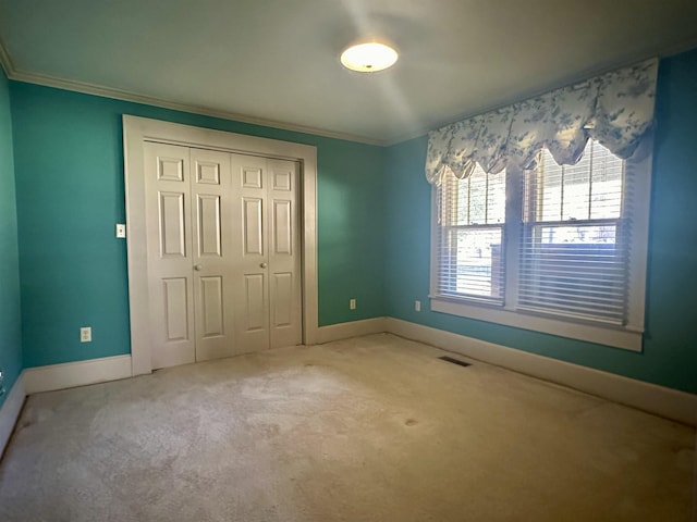 unfurnished bedroom featuring carpet floors, crown molding, and a closet