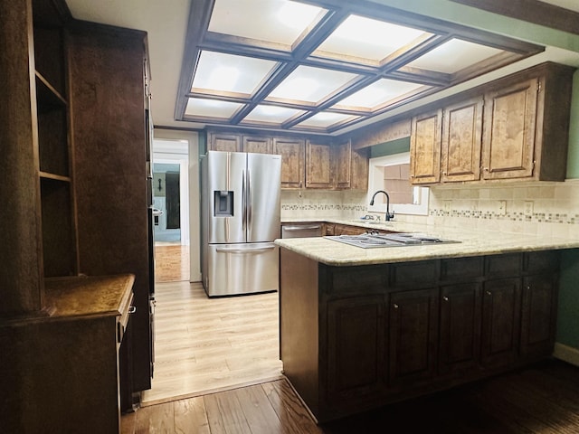 kitchen featuring kitchen peninsula, stainless steel appliances, light hardwood / wood-style flooring, and tasteful backsplash