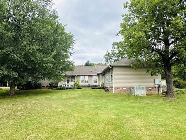 rear view of property featuring a yard and central AC unit