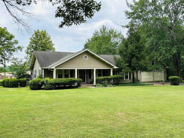 view of front of home featuring a porch, a front yard, and a garage