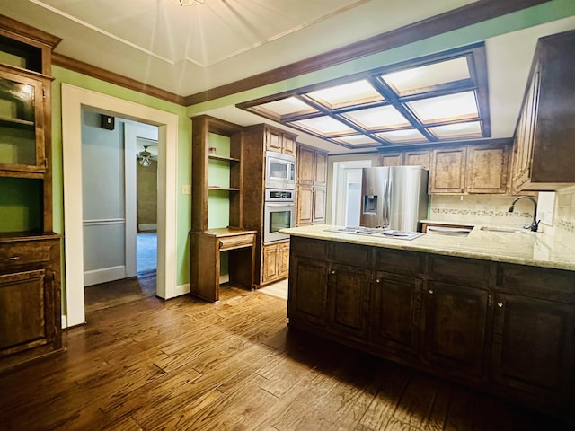 kitchen with light stone countertops, sink, decorative backsplash, appliances with stainless steel finishes, and light wood-type flooring