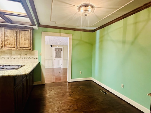 kitchen with tasteful backsplash, stainless steel gas stovetop, dark hardwood / wood-style floors, and ornamental molding