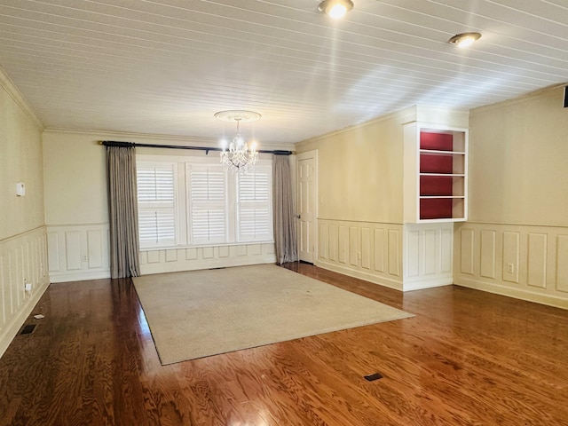 unfurnished room with wood-type flooring, crown molding, and an inviting chandelier