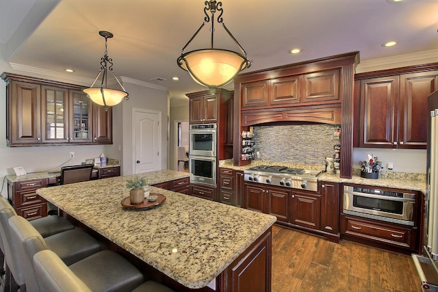 kitchen with pendant lighting, light stone countertops, a kitchen island, dark hardwood / wood-style flooring, and stainless steel appliances