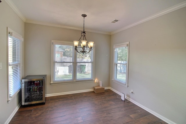 unfurnished dining area featuring wine cooler, crown molding, dark wood-type flooring, and a healthy amount of sunlight