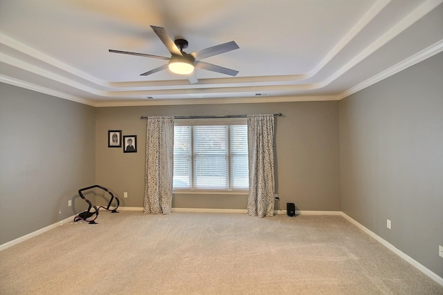 carpeted empty room featuring a raised ceiling, ceiling fan, and crown molding