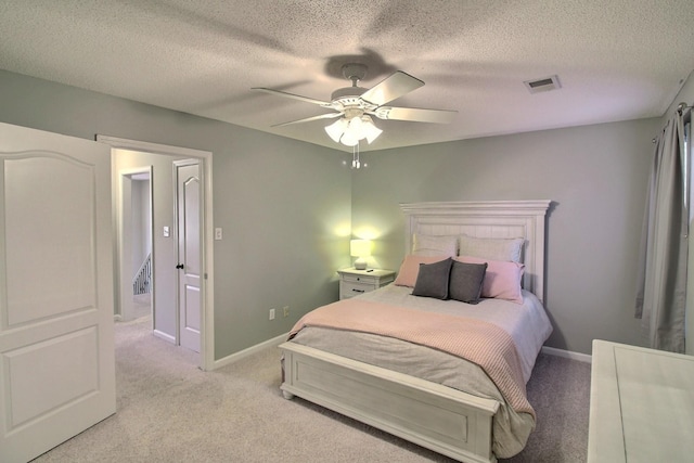 bedroom featuring a textured ceiling, light colored carpet, and ceiling fan