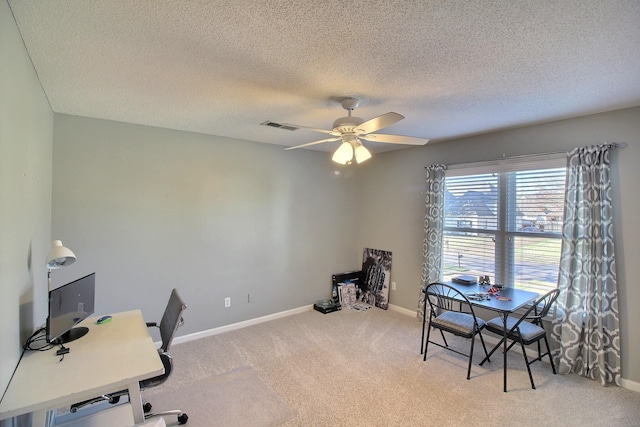 carpeted office space featuring ceiling fan and a textured ceiling