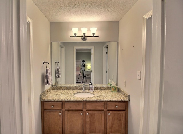 bathroom featuring a textured ceiling, vanity, and a notable chandelier