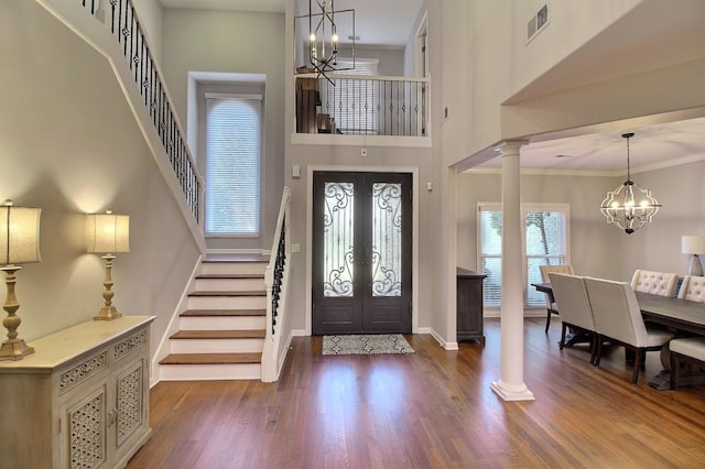 foyer entrance featuring ornate columns, french doors, dark hardwood / wood-style flooring, crown molding, and a towering ceiling