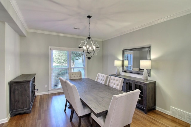 dining space featuring light hardwood / wood-style floors, an inviting chandelier, and crown molding