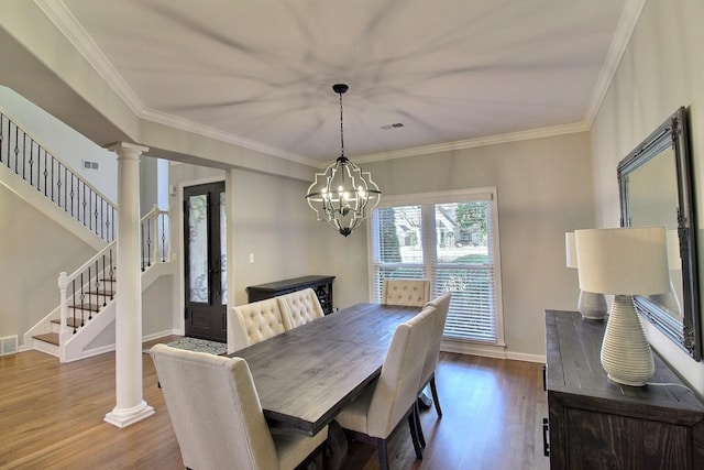 dining space with french doors, crown molding, hardwood / wood-style flooring, a chandelier, and decorative columns