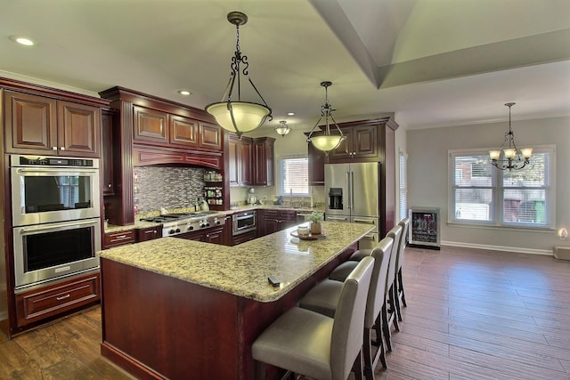 kitchen with dark wood-type flooring, a center island, stainless steel appliances, and a notable chandelier