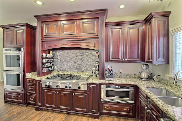 kitchen with light stone countertops, sink, dark hardwood / wood-style flooring, plenty of natural light, and appliances with stainless steel finishes