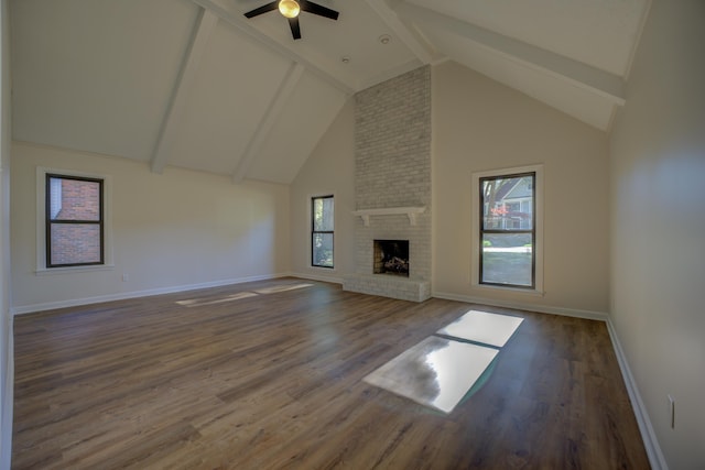 unfurnished living room with dark wood-type flooring, high vaulted ceiling, a healthy amount of sunlight, and a brick fireplace