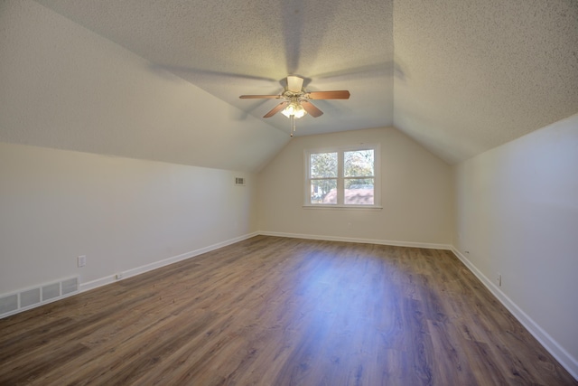 bonus room with a textured ceiling, ceiling fan, lofted ceiling, and dark wood-type flooring