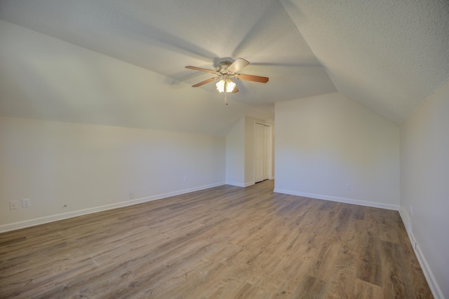 bonus room featuring a textured ceiling, light hardwood / wood-style flooring, ceiling fan, and lofted ceiling