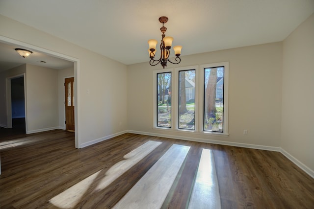 unfurnished room with dark wood-type flooring and a chandelier