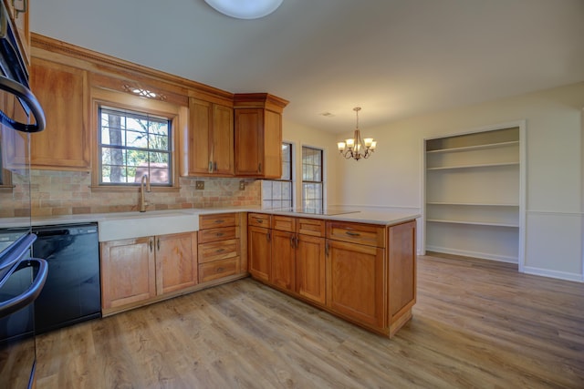 kitchen featuring tasteful backsplash, kitchen peninsula, decorative light fixtures, and black dishwasher