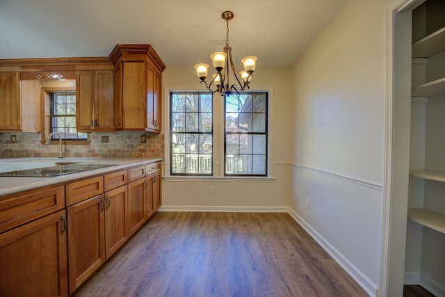 kitchen with tasteful backsplash, black electric cooktop, pendant lighting, hardwood / wood-style flooring, and a chandelier