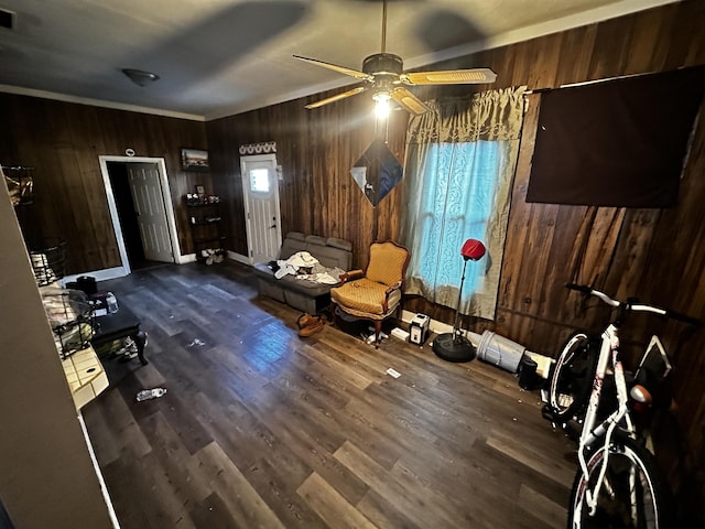 interior space with ceiling fan, wood walls, dark hardwood / wood-style flooring, and ornamental molding