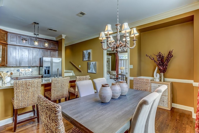 dining room with ornamental molding, dark wood-type flooring, and an inviting chandelier