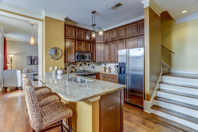 kitchen with sink, light hardwood / wood-style flooring, kitchen peninsula, a breakfast bar area, and appliances with stainless steel finishes