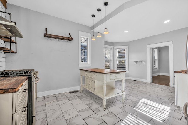 kitchen with wooden counters, a kitchen bar, decorative light fixtures, white cabinets, and stainless steel range with gas cooktop