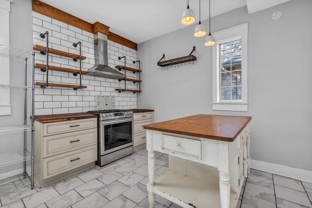 kitchen featuring wooden counters, wall chimney exhaust hood, stainless steel range, tasteful backsplash, and decorative light fixtures