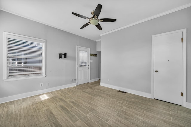 spare room featuring ceiling fan, a healthy amount of sunlight, crown molding, and light hardwood / wood-style flooring