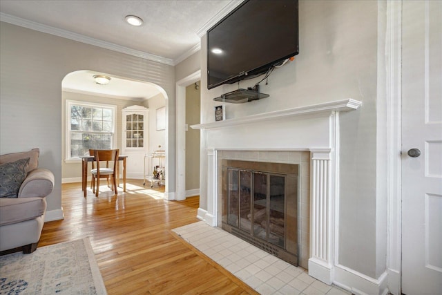 living room with a tile fireplace, light hardwood / wood-style floors, and crown molding