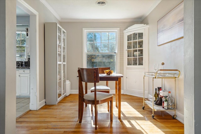 dining room with crown molding, plenty of natural light, and light hardwood / wood-style floors