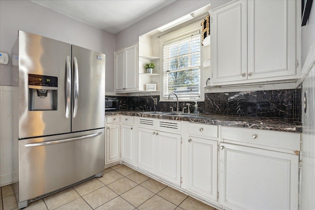 kitchen featuring sink, light tile patterned floors, stainless steel fridge with ice dispenser, backsplash, and white cabinets