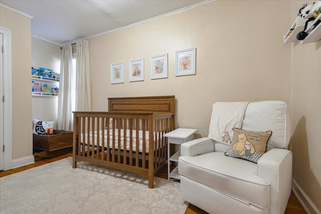 bedroom featuring crown molding, wood-type flooring, and a crib