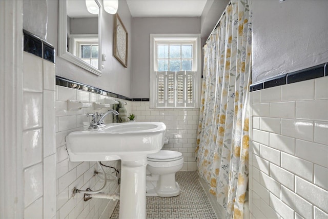 bathroom with tile patterned floors, sink, toilet, tile walls, and walk in shower